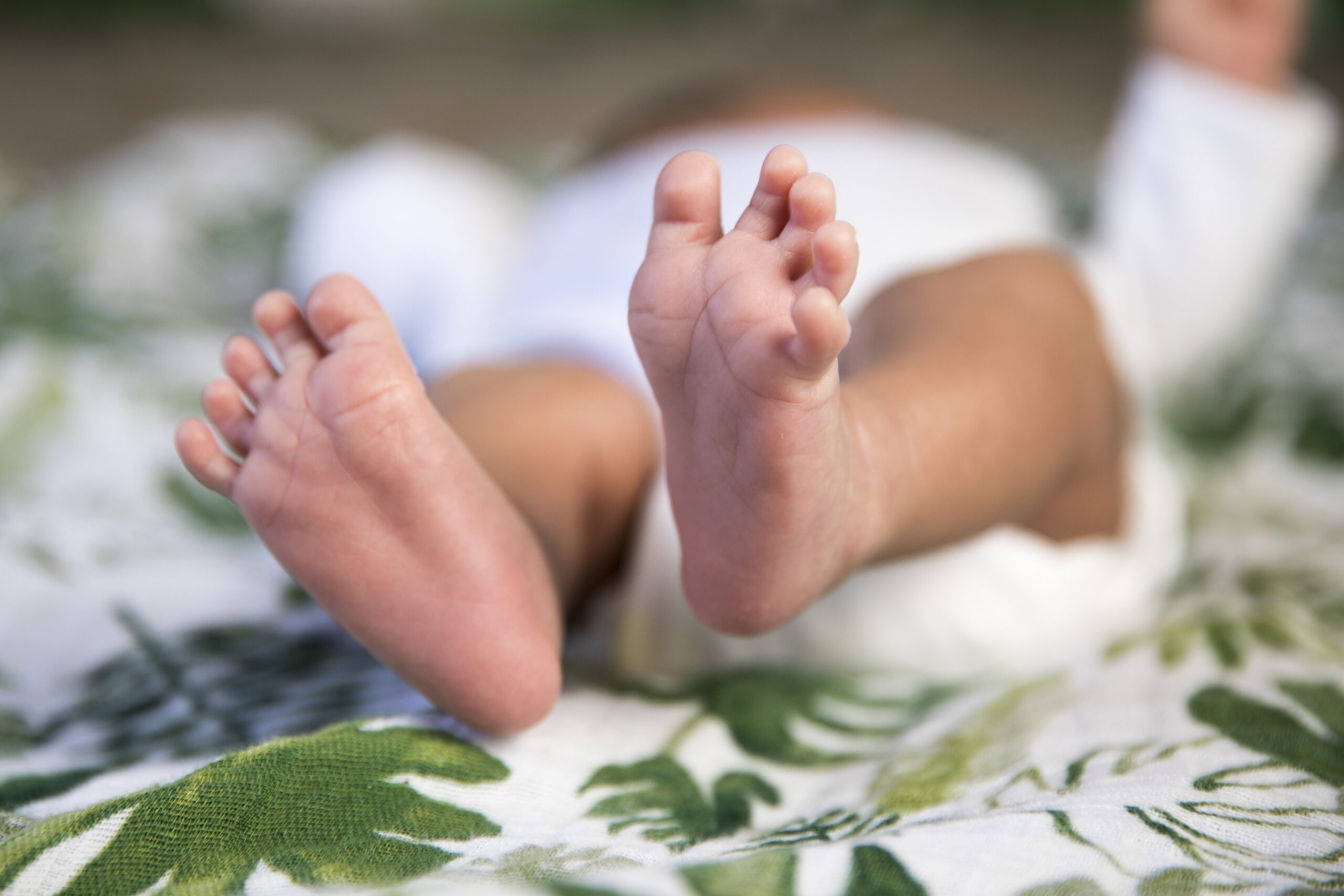 baby-feet-on-a-blanket-patterned-with-green-leaves-scaled